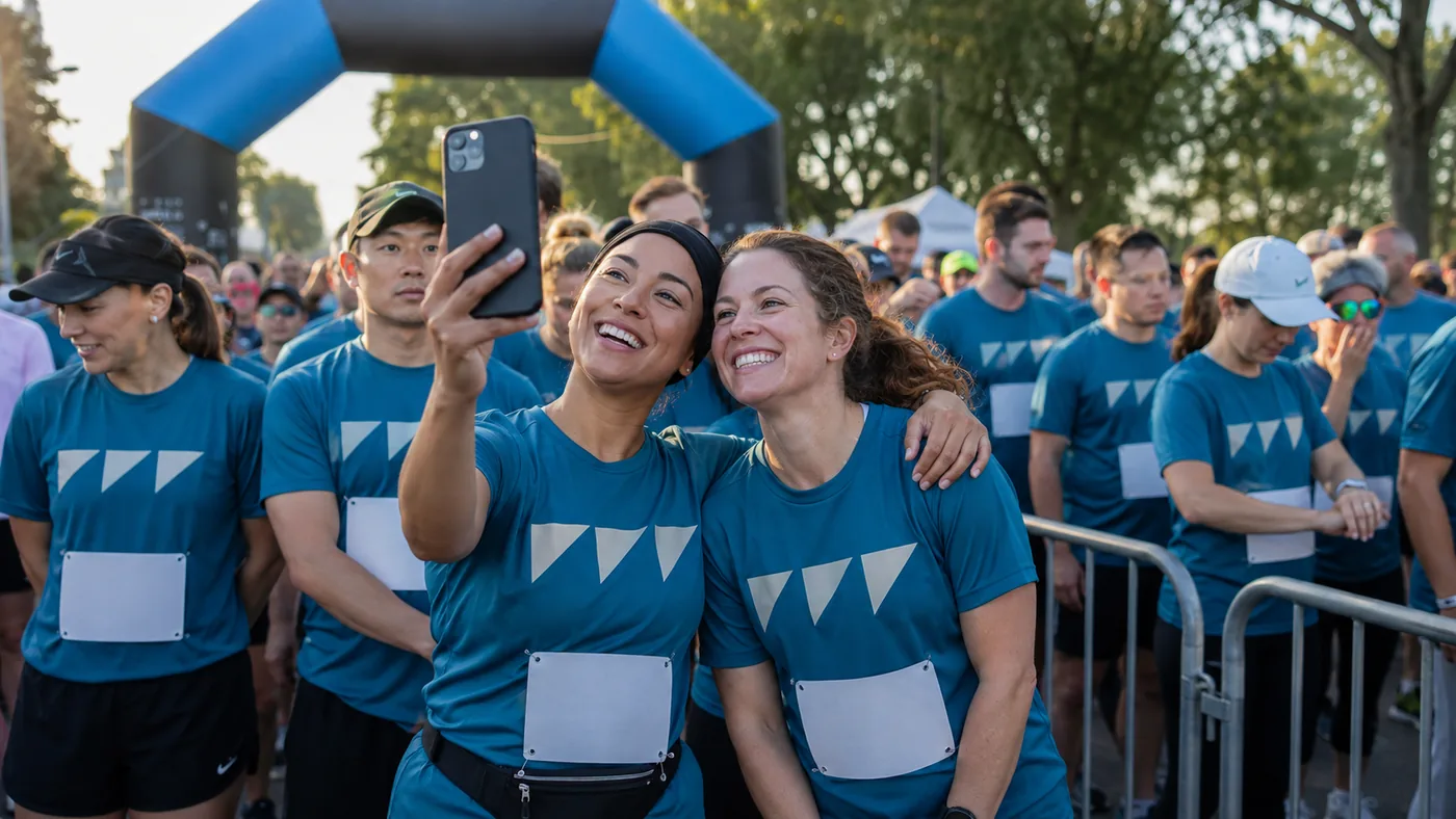 Runners packed at the Foundry 5K start line in matching printed race tees under the start arch